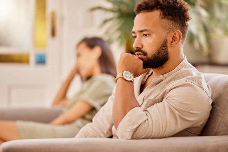 Sad couple sitting on opposite ends of couch
